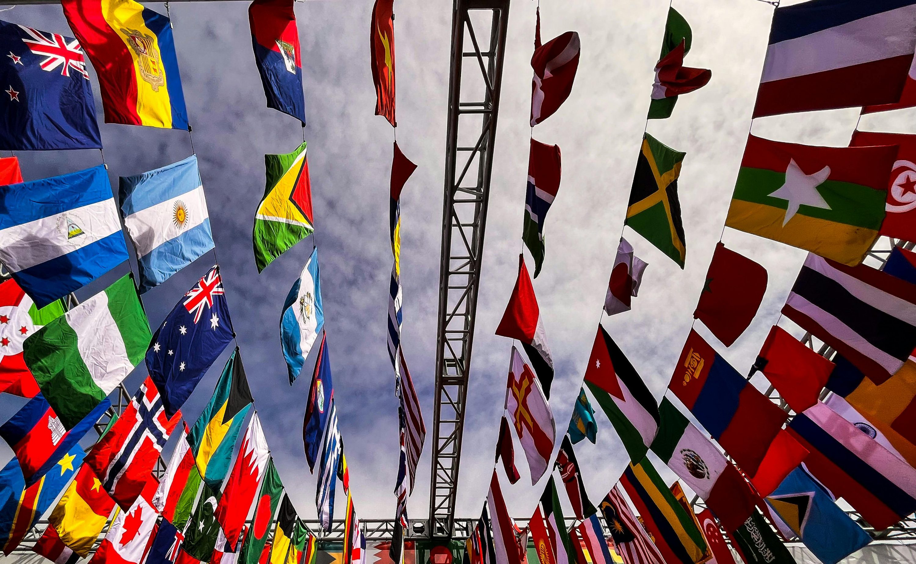 pexels-photo-12226152-12226152 A dynamic low angle shot of various international flags hanging outdoors against a cloudy sky.